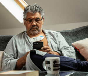 Man relaxing at home with Sensium Patch and mobile phone app